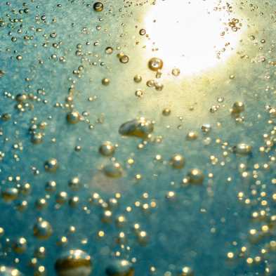 Bubbles in a blue liquid through which light shines from above.